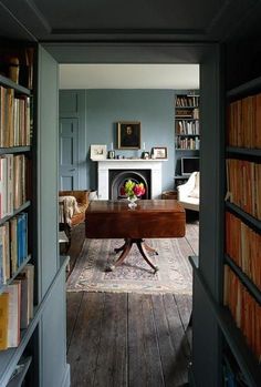 an open door leading to a library with bookshelves and a fireplace in the background