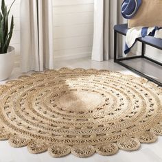 a large round rug on the floor in front of a chair and potted plant