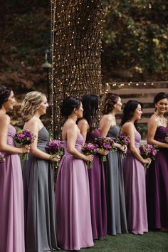 a group of women standing next to each other in long purple and grey dress dresses