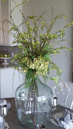 a vase filled with flowers sitting on top of a dining room table covered in silverware