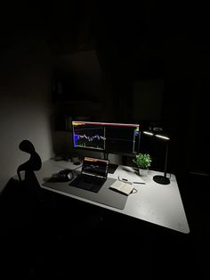 a desk with a laptop and monitor lit up in the dark