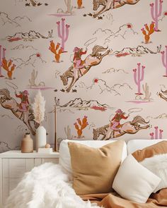 a white bed topped with pillows next to a wallpaper covered in pink and orange