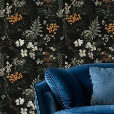 a blue couch sitting in front of a black wallpaper with white and orange flowers