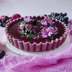 a chocolate tart topped with fresh blueberries and flowers