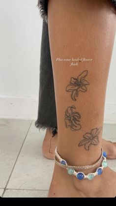 a woman's foot with tattoos on her left leg and blue beads around the ankles