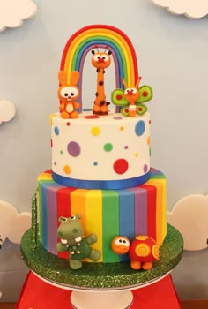 a multi - tiered cake decorated with animals and rainbows on top of a table