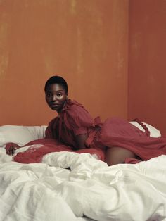 a woman in a red dress laying on a bed