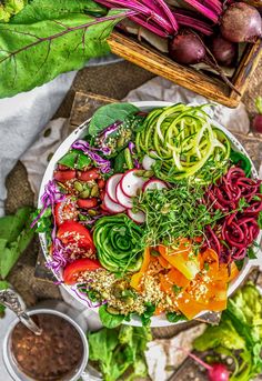 a bowl filled with lots of veggies next to other vegetables and sauces