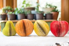 three different colored apples sitting on top of a white cloth covered table with potted plants in the background