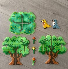 several pieces of perler bead art on a wooden floor, including trees and animals