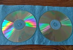 two cd's sitting on top of a blue towel next to each other in front of a wooden table