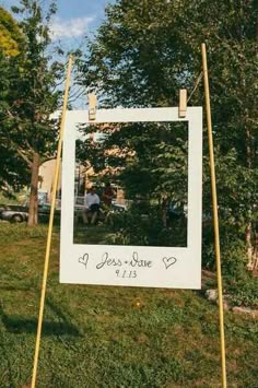 a sign that is sitting in the grass with a photo frame on top of it