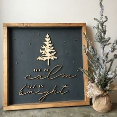 a wooden sign that says all is calm and bright next to a potted plant