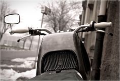 a motorcycle parked next to a building with snow on the ground and trees in the background