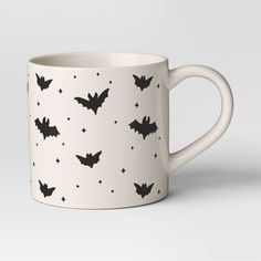 a white coffee mug with bats printed on the side and stars in the middle, all over it