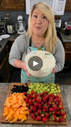 a woman standing in front of a platter of fruit