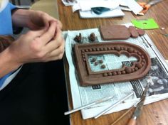 a woman is making a chocolate cake with icing and decorations on the table in front of her