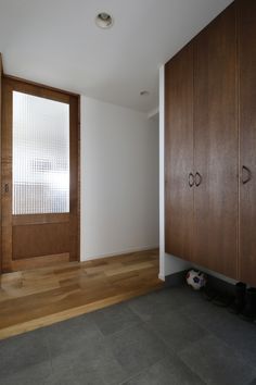 an empty room with wooden doors and hard wood flooring on the side, next to a pair of black shoes