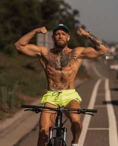 a shirtless man on a bicycle flexing his muscles