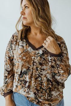 Make a statement with this mid to plus-size BREEZY FALL PATTERNED BLOUSE, a luxurious piece that combines elegance and comfort seamlessly. With its all-over print, brown piping, and v-neckline, it will become the center of attention, while its soft fabric, long sleeves, and flattering silhouette will keep you stylish. Layer it under your favorite pieces for a look that’s both timeless and fashionable. Fits true to size. Misty is wearing a size 12. Want more information about the model? Visit our Patterned Blouse, Fall Patterns, Arm Sleeve, Blouse Patterns, Body Types, Soft Fabric, Piping, Soft Fabrics, Size 12