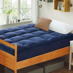 a bed that has a blue mattress on top of it in front of a window