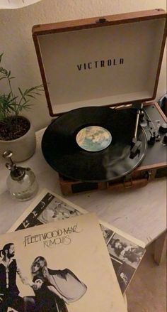 an old record player sitting on top of a table next to other records and vases