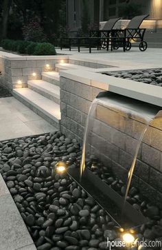 an outdoor fountain with water running from it's sides and lit up by lights