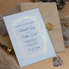 a wedding card with a wax stamp on it next to an envelope and some flowers