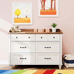 a child's room with pink walls, white dresser and colorful rug on the floor