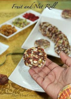 a person holding up some food in front of other plates with nuts and fruit on them