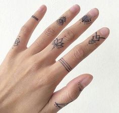 a woman's hand with tattoos on it and two fingers in the foreground