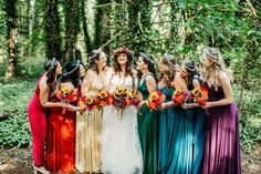 a group of women standing next to each other in front of trees and bushes wearing colorful dresses