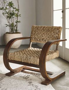 a wicker chair sitting on top of a rug next to a potted plant