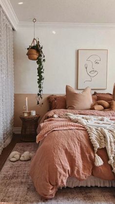 a bedroom with a large bed covered in pink linens and pillows, hanging from the ceiling