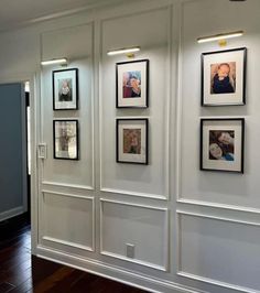 a wall with several pictures hanging on it's sides and some lights above them