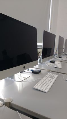 a row of computer monitors sitting on top of a white desk next to each other