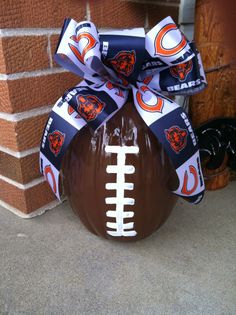 a football ornament with a bow on the front of it, tied to a brick wall