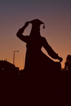 the silhouette of a person wearing a graduation cap and gown in front of a sunset