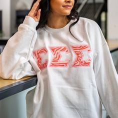 This unique & trendy Pink & Orange Swirls Greek Letter Sorority Chapter Gildan Crew Neck Sweatshirt is sure to stand out on any campus!  Grab one for you, your favorite sister, or a group of sisters (chapter discounts offered - see below for more information). Pictures Featuring:  1-2. White sweatshirt w/ Light Pink background fabric color (Sigma Sigma Sigma)  There are 4 parts to your Greek Letter Sweatshirt: 1. T-shirt Color 2. T-shirt Size 3. Background Fabric Letter Color - This is the fabric behind the printed fabric. Each greek letter sweatshirt is double stitched (two layers of fabric)  4. Greek Organization  - MAX 3 Greek letters  *please refer to the Greek Letter Shirt Info diagram for directions if you are confused* Please include your Sweatshirt Color AND Greek organization in t Spring Sorority Long Sleeve Tops, White Sorority Sweatshirt With Letter Print, White Crew Neck Sorority Sweatshirt, White Sorority Crew Neck Sweatshirt, White Sorority Top For Spring, Sorority Long Sleeve Relaxed Fit Tops, Sorority Long Sleeve Tops For College, Long Sleeve Tops For College Sororities, Sorority Letters Sweatshirt