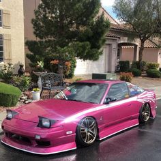 a pink car parked in front of a house