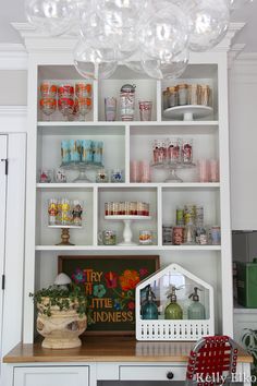 a white shelf filled with lots of glassware and bottles on top of it's shelves