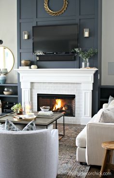 the living room is decorated in white and gray with a fireplace, tv, couches, and coffee table