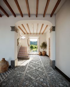 an entry way with stone steps and potted plants on either side, leading to a pool