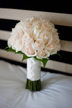 a bouquet of white roses is sitting on a bed with black and white striped sheets