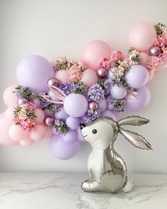 a balloon filled with flowers and balloons in the shape of a bunny sitting on top of a table