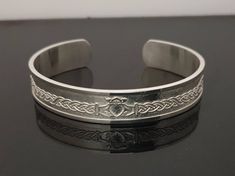 "☘️DESCRIPTION: Sterling Silver Claddagh cuff bangle is a unique design with beautiful Celtic Knot detail, including a feature love knot on either side of the band. It is a heavyweight bangle made from 2mm thick Sterling Silver. ☘️SPECIFICATIONS: Width 15mm Weight 70 grams Bracelet length 6.0\" - 8.5\". Any other length available upon request. ☘️WHERE IS IT MADE? Each Claddagh cuff bangle is individually handcrafted in my workshop in Dublin, Ireland. By handcrafting each one to order I can ensur Hallmarked Adjustable Cuff Bracelet For Gift, Adjustable Hallmarked Cuff Bracelet As Gift, Polished Finish Cuff Bracelet As Gift, Adjustable Hallmarked Cuff Bracelet Gift, Hallmarked Cuff Bangle Bracelet As Gift, Hallmarked Bangle Cuff Bracelet For Gifts, Adjustable Hallmarked Cuff Bracelet For Anniversary, Polished Band Jewelry Gift, Polished Band Jewelry For Gifts