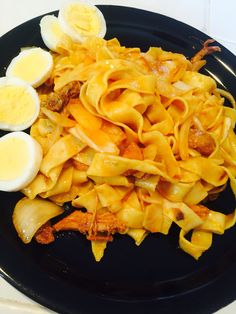 a black plate topped with pasta and hard boiled eggs