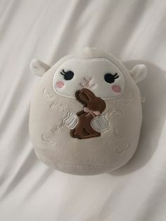 a white stuffed animal with a brown bear on it's back and eyes closed