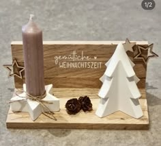 a small wooden box with a candle and christmas tree decoration on the front, next to it is a pine cone