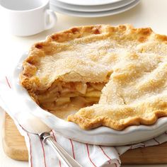 a pie sitting on top of a wooden cutting board next to a cup and saucer